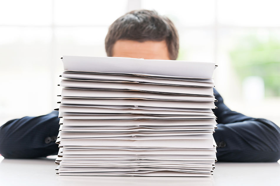 photo of a business man in Canada hiding behind a stack of papers for hiring employees for his business